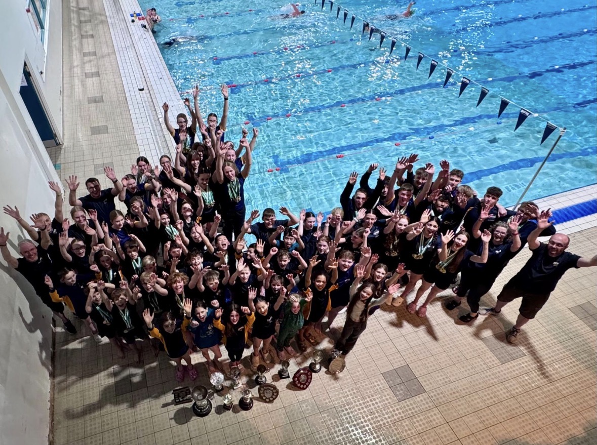 Grantham Swim Club swimmers and coaches celebrating at the Club County Qualifiers with trophies by the pool